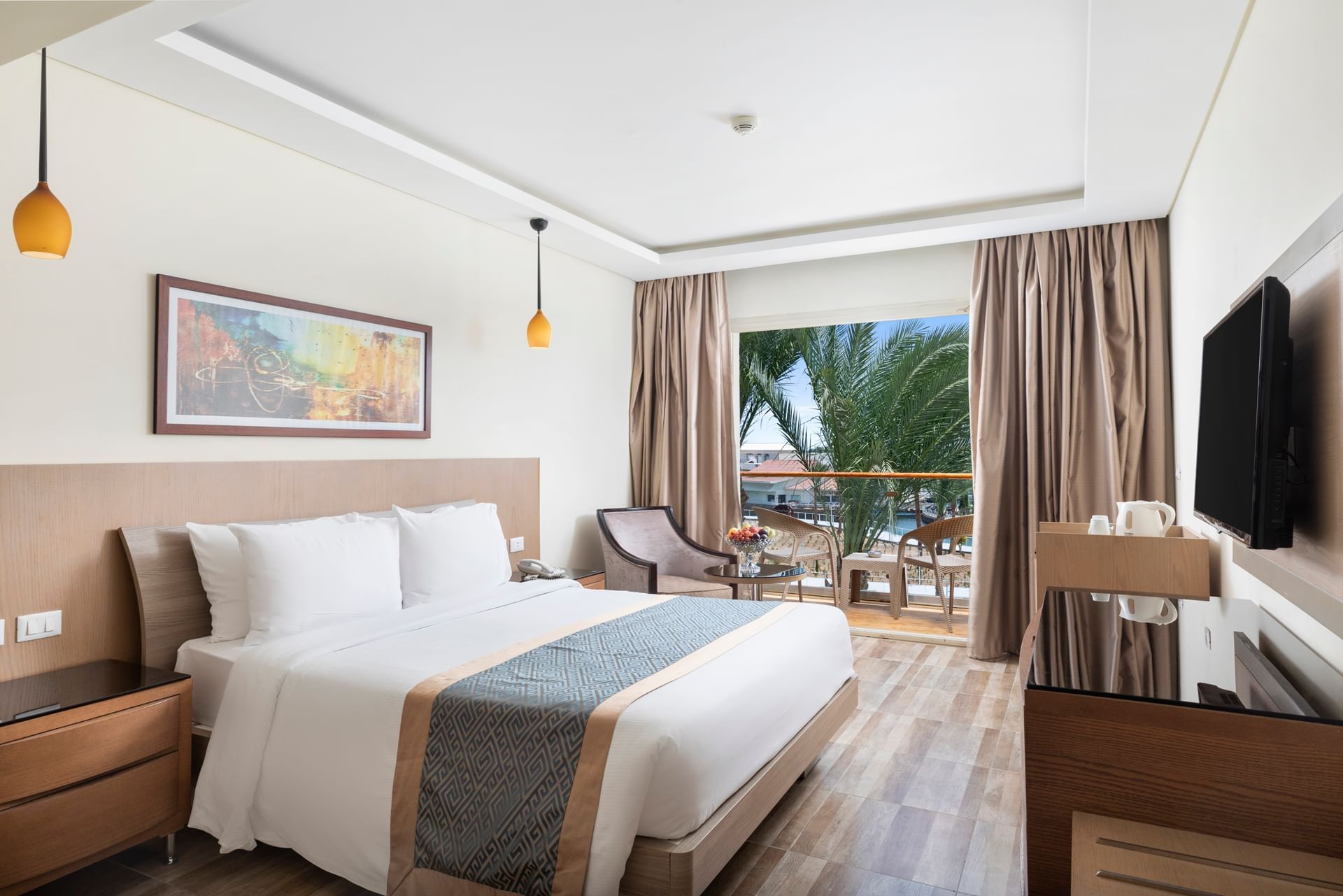 Modern eingerichtetes Hotelzimmer mit Doppelbett, Sitzbereich, Balkon mit Blick auf Palmen und Resortanlagen im Pickalbatros Dana Beach Resort.