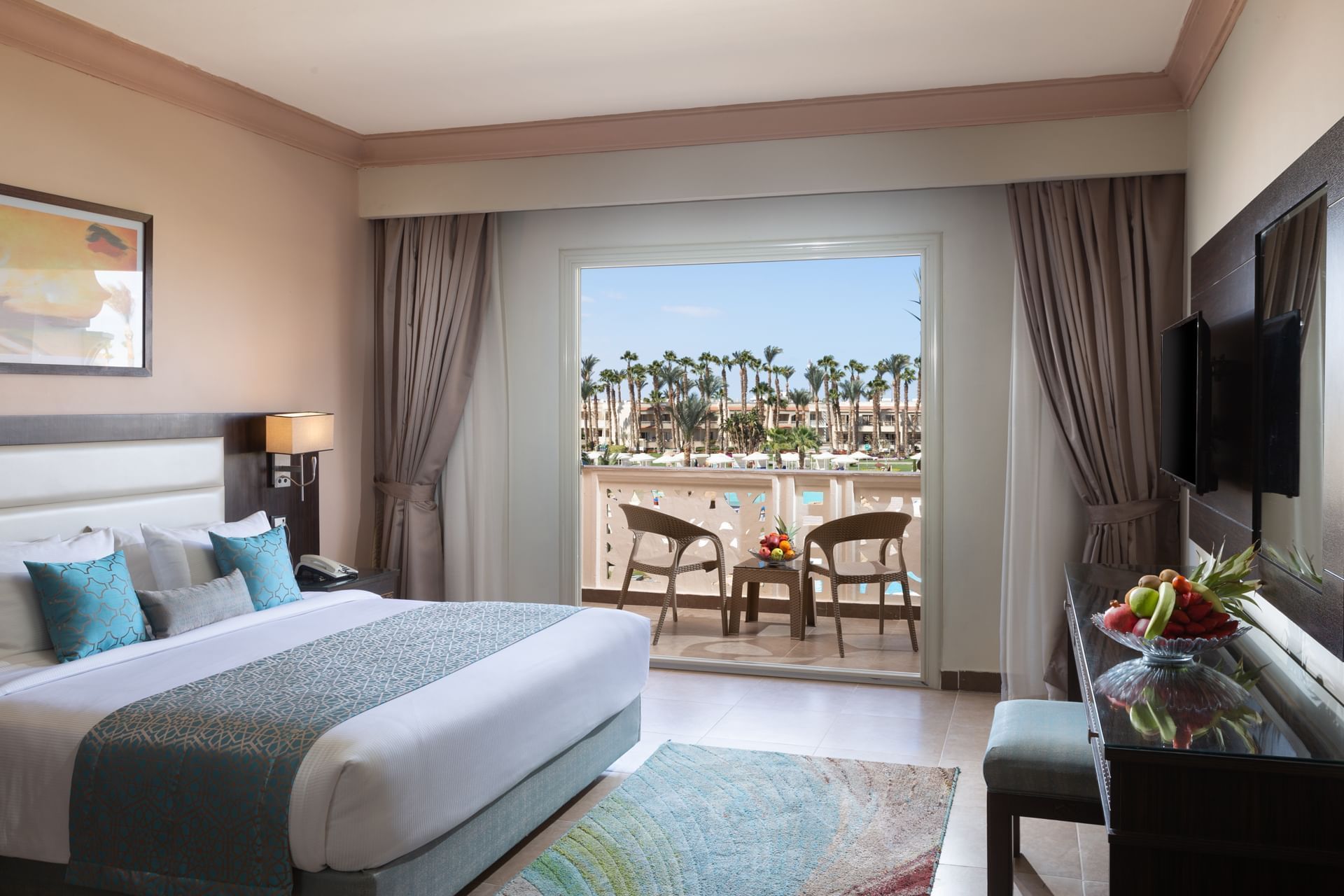 Modern eingerichtetes Hotelzimmer mit Doppelbett, Balkon und Blick auf Palmen und Pool im Pickalbatros Palace Resort.