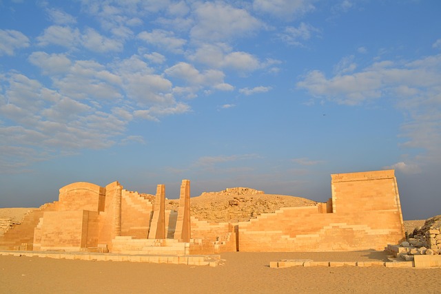 Ruinen von Sakkara in warmem Wüstenlicht unter blauem Himmel – antike Steinmauern und Säulen vor sandiger Landschaft.