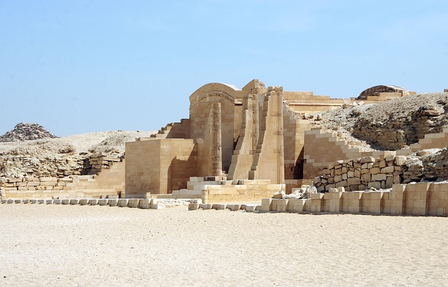 Sandfarbene Ruinen und Säulen des Nekropolen-Komplexes von Sakkara in der Wüste, unter klarem Himmel.