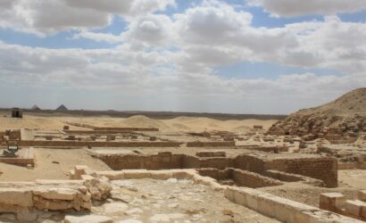 Freigelegte Mauerreste in der Nekropole von Sakkara mit Pyramiden am Horizont.